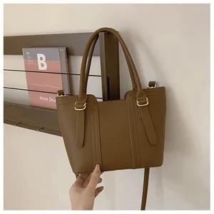 Close-up of brown litchi grain leather tote bag with elegant golden D-ring accents