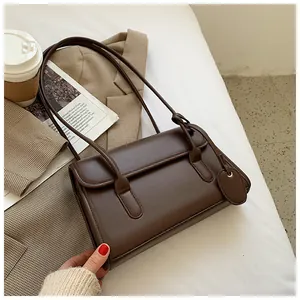 Detailed view of a brown minimalist leather shoulder bag on a stylish plaid blazer