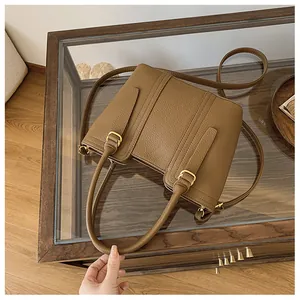 Detail of caramel lychee leather handbag with golden hardware on a wooden table