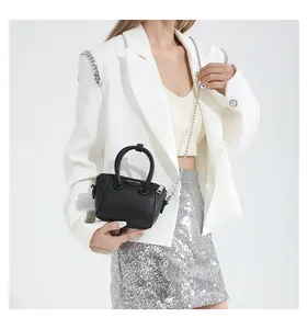 Mini black lychee pattern handbag with silver chain shown as worn on a model