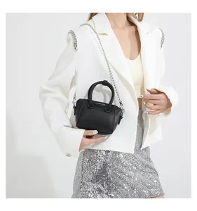 Detail of black pebbled leather mini bag with metal logo and silver chain strap