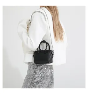 Detail of mini black lychee leather handbag featuring chunky silver chain and logo