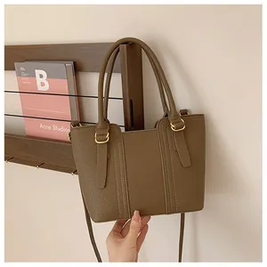 Detail of brown lychee grain leather tote with gold hardware and vertical stitching