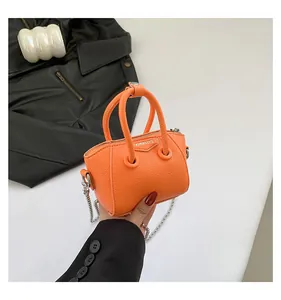 Detail of mini orange lychee textured handbag with silver chain and fashion text logo