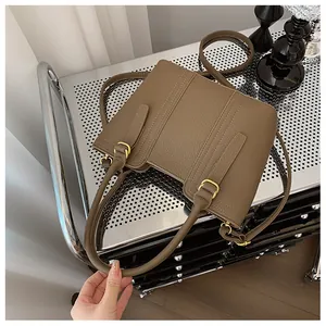 Detailed shot of brown textured leather handbag with gold-tone hardware and adjustable strap