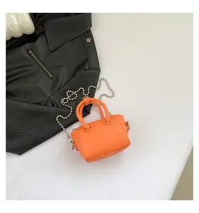 Close-up of orange litchi grain mini Boston bag with silver chain strap and top handles