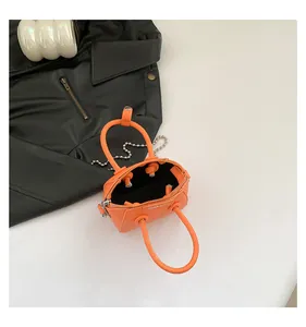 Top view of orange mini handbag with litchi grain texture and silver bead chain strap
