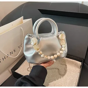 Sac à main argenté plissé avec perles décoratives en marbre dans une boîte cadeau noire