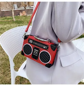 Detail of red radio-shaped crossbody bag with vintage dial and silver hardware accents