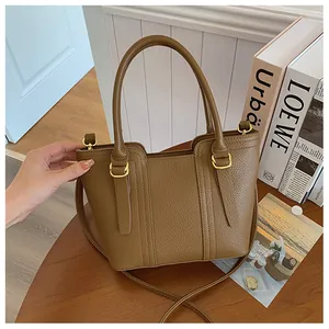 Close-up of brown litchi pattern leather handbag with gold hardware and top handles