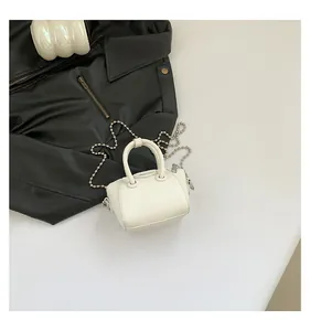 Detail of white lychee leather mini bag featuring silver ball chain and top handles