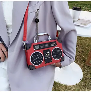 Detail of red boombox shaped crossbody bag with silver handle and boom lettering