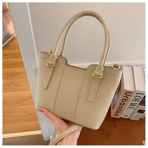 Detailed macro view of beige lychee texture leather handbag with gold metal hardware