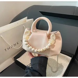 Détail du sac à main rose clair avec perles marbrées, poignée anneau et chaîne argent