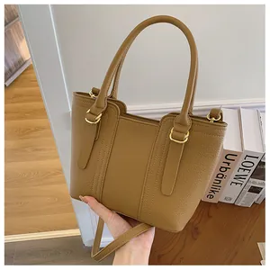 Detail of brown litchi pattern leather handbag with gold metal rings and dual handles
