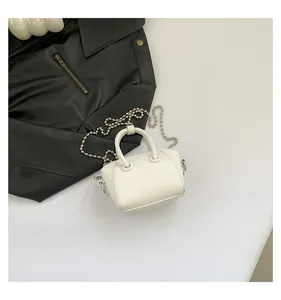 Detailed macro view of white pebble leather texture and metal bead chain on mini handbag