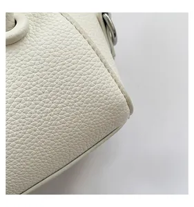 Detailed close-up of white pebbled leather texture and silver metal hardware on a mini bag