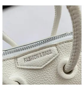 Close-up of silver metal zipper and brand label on white pebble leather mini bag