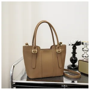 Detail of brown litchi textured leather tote with golden hardware and vertical stitching