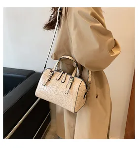 Detalle de bolso boston beige con relieve de cocodrilo, asas dobles y hebilla metálica