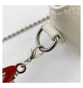 Detail of white lychee leather texture and shiny silver chain on small crossbody bag