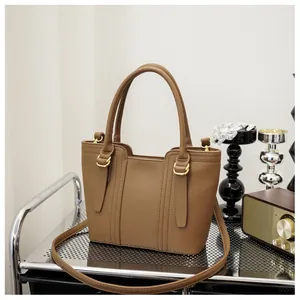 Detailed shot of brown lychee grain leather handbag with gold hardware on a shelf
