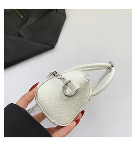 Close-up of white mini handbag featuring pebbled leather texture and metal ball chain