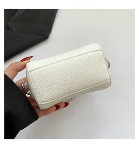 Close-up of white pebble grain mini bag featuring silver metal D-ring and precise stitching