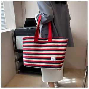 Side view of striped canvas tote bag with red handles and fashion rag logo label
