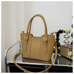 Detail of khaki leather handbag with litchi grain texture and gold metal hardware