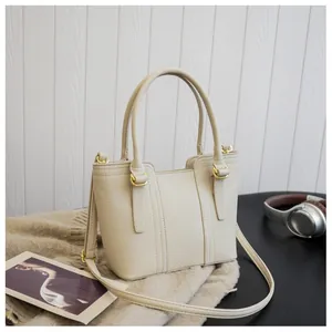 Detail of cream-colored bucket bag showing lychee leather texture and gold hardware