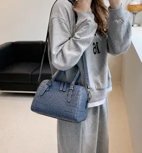 Detalle de bolso Boston azul con diseño de cocodrilo, asas y correa ajustable