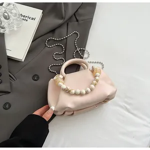 Détail du sac nuage plissé rose avec poignée en perles marbre sur blazer gris