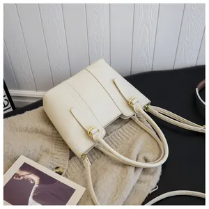 Detail of creamy white pebble leather handbag with gold hardware on knit background