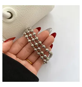 Detail of triple-layer silver bead bracelet with polished finish held by hand