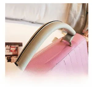 Detail of pink quilted leather bag featuring cream contrast handle and gold metal ring