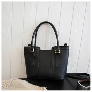 Close-up of black lychee grain leather handbag with elegant gold hardware and dual handles