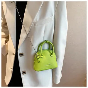Detail of neon green mini shell crossbody bag with litchi texture and metal chain