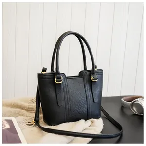 Detail of black pebbled leather texture on handbag with gold ring hardware and dual handles