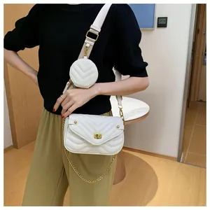 Detail van witte gewatteerde crossbodytas met een kleine ronde portemonnee en gouden ketting