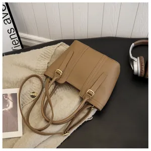 Detail of lychee pattern leather bucket bag with gold-tone buckle and adjustable strap