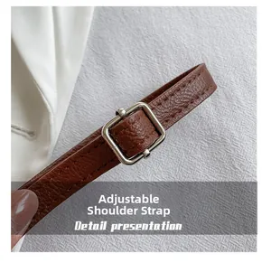 Gros plan sur la bandoulière réglable en cuir marron avec boucle argentée et grain litchi