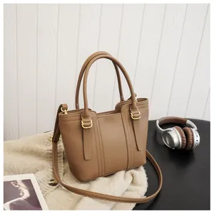 Detail of tan pebble leather bucket bag with gold hardware on soft knit fabric
