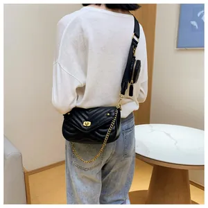 Vue détaillée d'un sac bandoulière matelassé noir avec sangle large et mini porte-monnaie