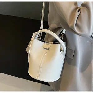 Detail of cream bucket bag with lychee texture and silk scarf handle on model