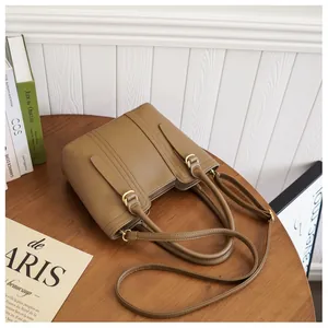 Close-up of tan lychee grain leather bucket bag with gold hardware on a wooden table