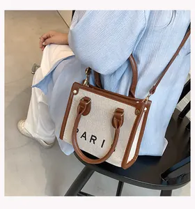 Detalle del bolso tote de lona con ribete de cuero marrón y letras de París en el lateral