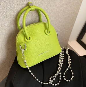 Neon green mini handbag with lychee texture, circular handles and silver chain strap