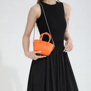 Mini orange lychee leather handbag with metal chain strap shown on a model