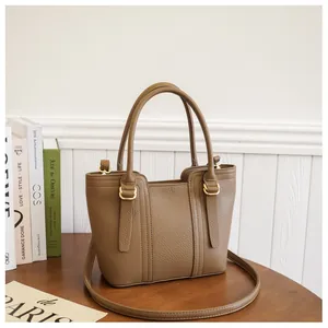 Detail of taupe pebbled leather bucket bag with gold hardware on a wooden table